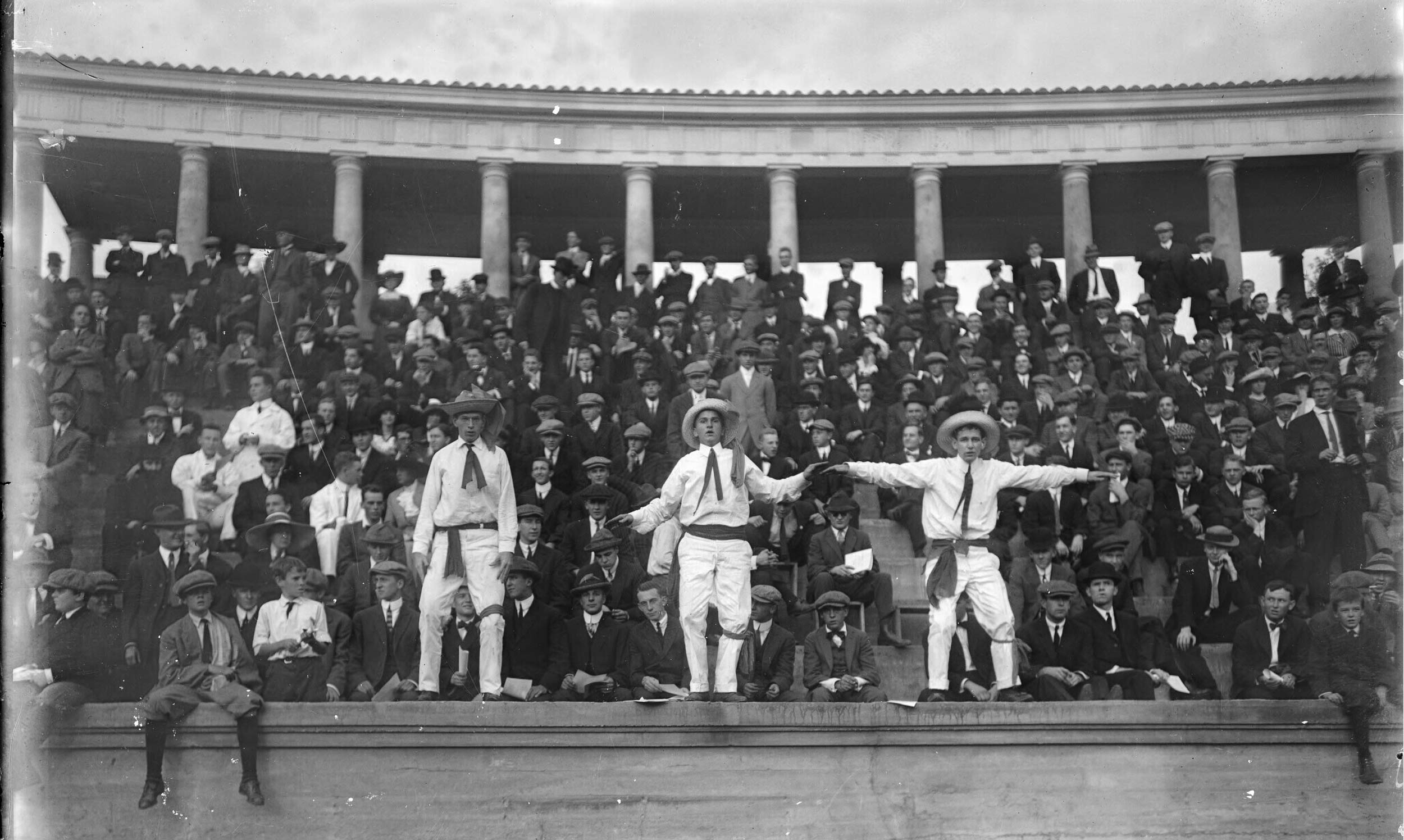 A vintage photo of a crowd watching a football game. Everyone is wearing suits and hats.