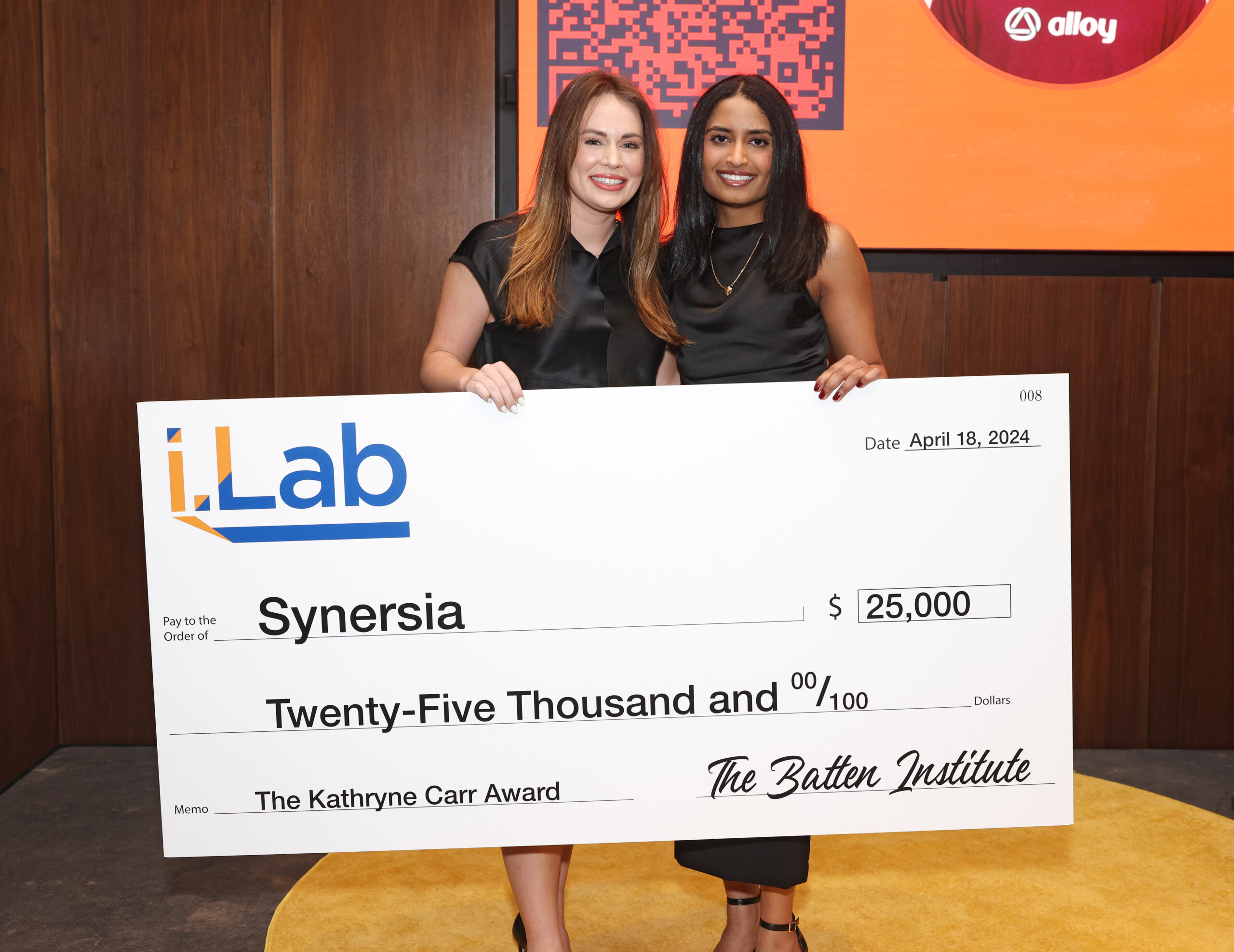 A photo of two women holding an enlarged check.