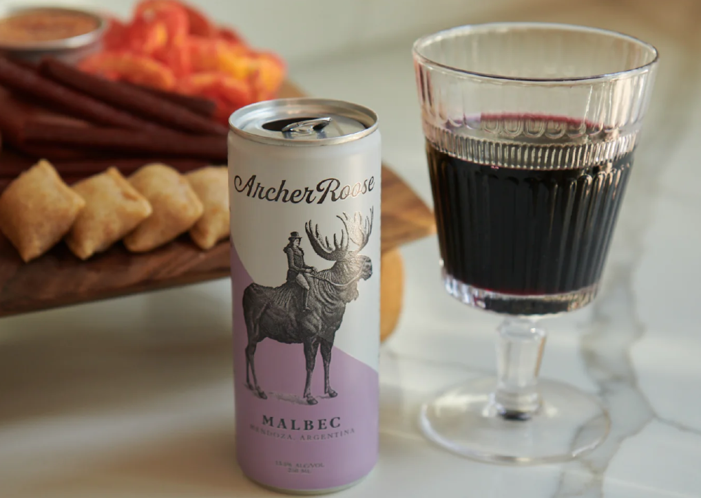 A photo of a can of malbec next to a glass of wine.