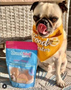 A photo of Munchbird treats and a dog.