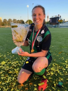 Betsy Brandon memegang trofi dengan confetti di mana -mana.